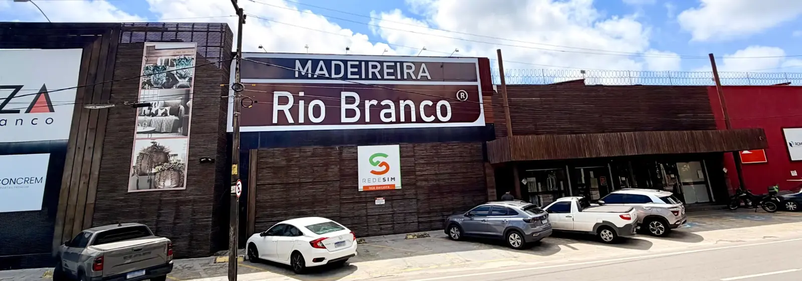 Fachada da Madeireira Rio Branco na Avenida Governador Raul Barbosa, com o letreiro e carros estacionados na frente