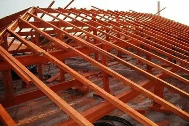 Estrutura de telhado em madeira com caibros e ripas vistos por baixo